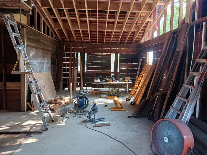Construction site interior with ladders, tools, and wooden framing