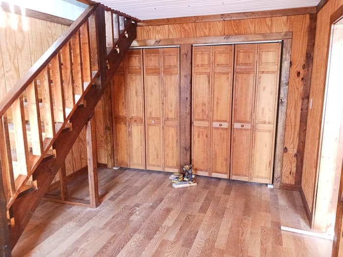 Wooden interior with stairs and multiple closed closet doors