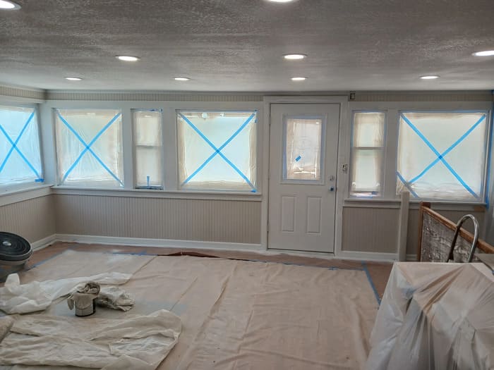Room in renovation with windows taped and floors covered in drop cloths